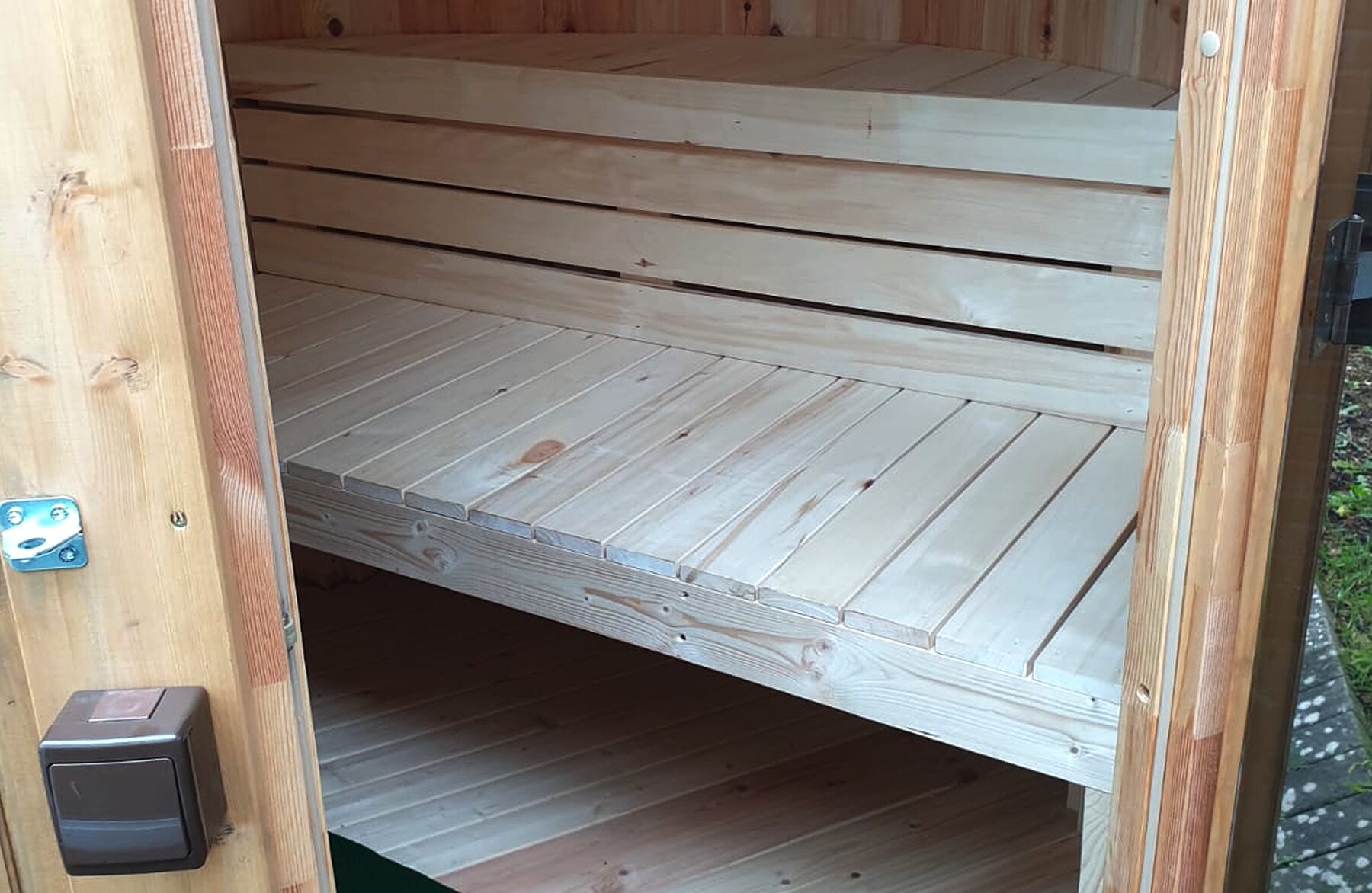 Innenansicht der Feuerbad Sauna VESTA mit hellen Holzbänken auf zwei Ebenen, klarer Holzstruktur, massiver Bauweise und natürlicher Holzoptik in einem kompakten Saunaraum