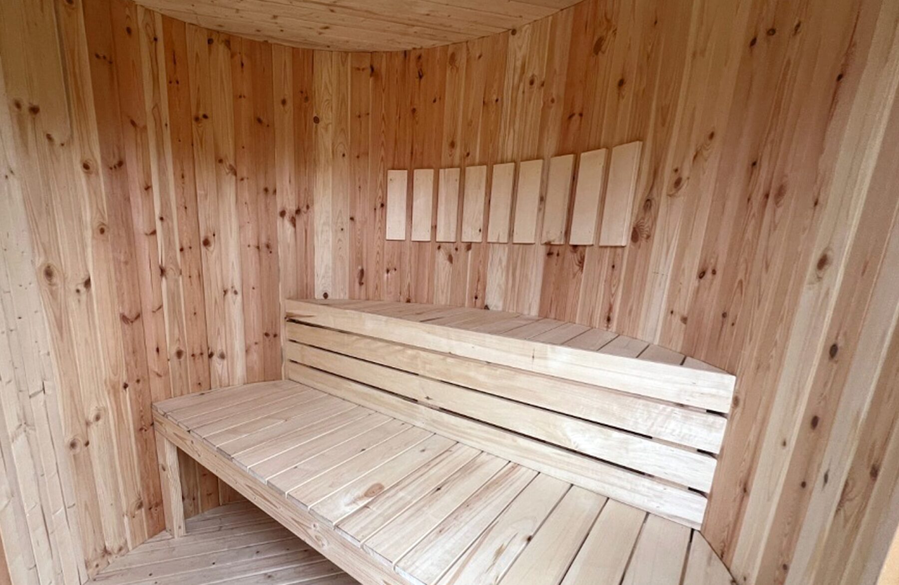 Innenansicht der Feuerbad Sauna VESTA mit heller Holzverkleidung, zweistufigen Holzbänken, ergonomischer Sitz- und Liegefläche sowie ruhiger, natürlicher Holzoptik im Saunaraum